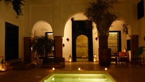 A courtyard with a pool, arches, potted plants, and seating areas. - Riad Magellan (Marrakech)