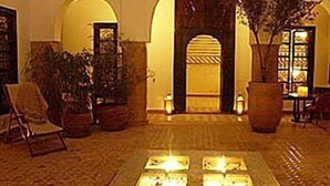 A lobby with a tiled floor, a central fire feature, and a doorway leading to another room. - Riad Magellan (Marrakech)