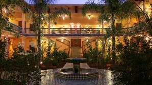 A courtyard with a fountain, surrounded by plants and a tiled floor.