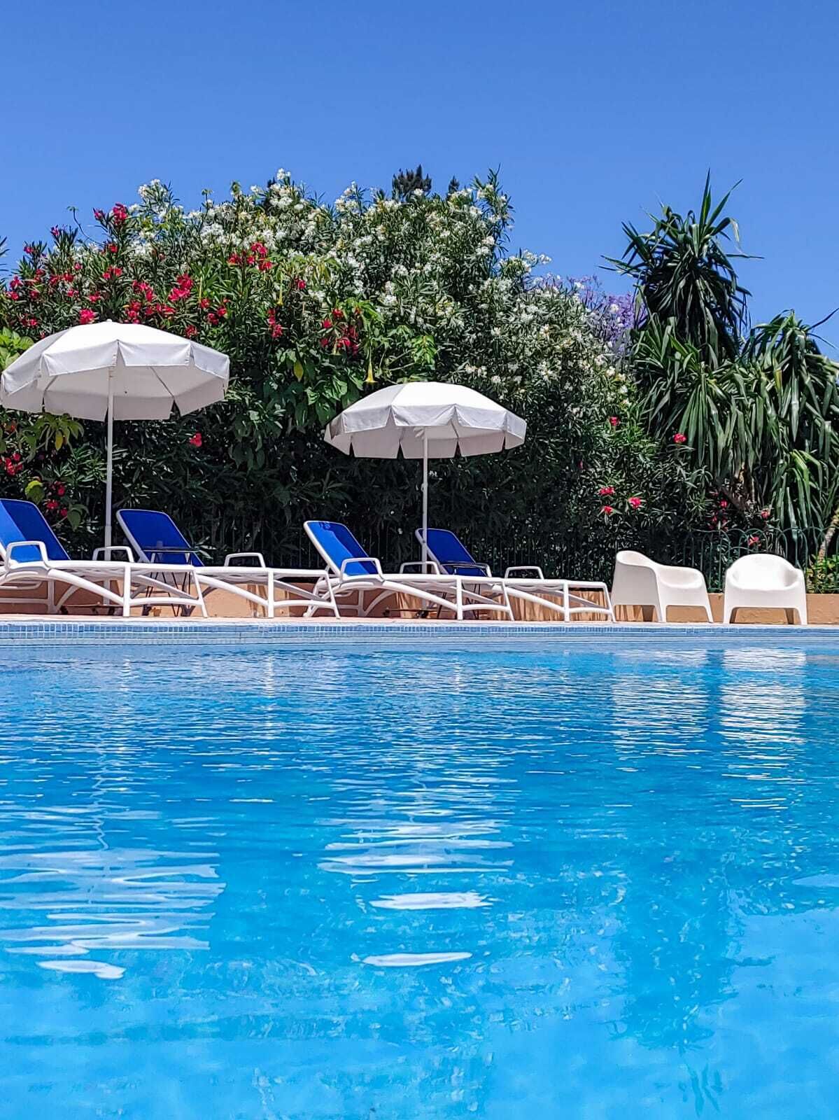 Una piscina al aire libre, sombrillas, tumbonas