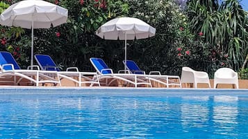 Una piscina al aire libre, sombrillas, tumbonas