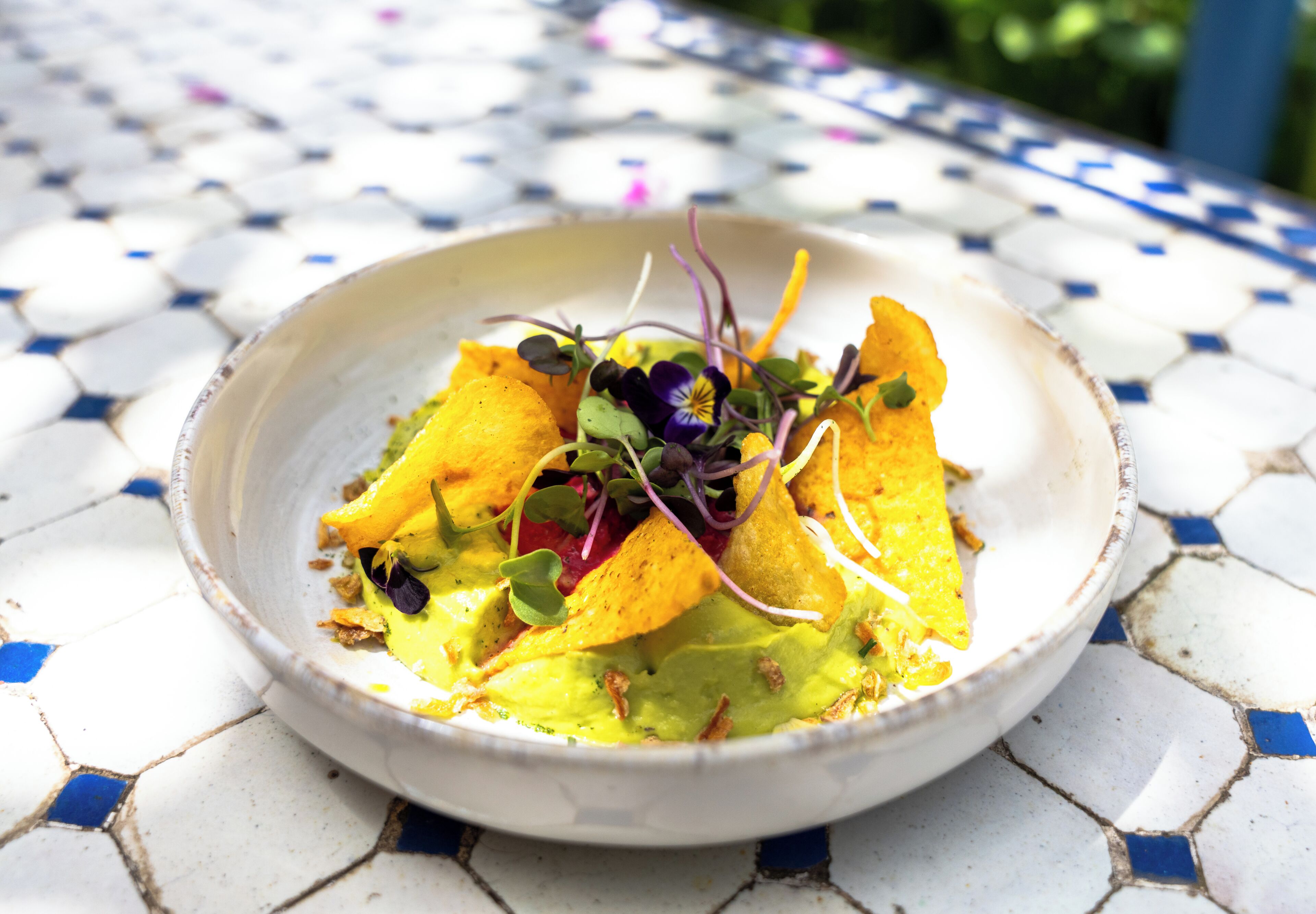 A bowl of food on a tiled table.