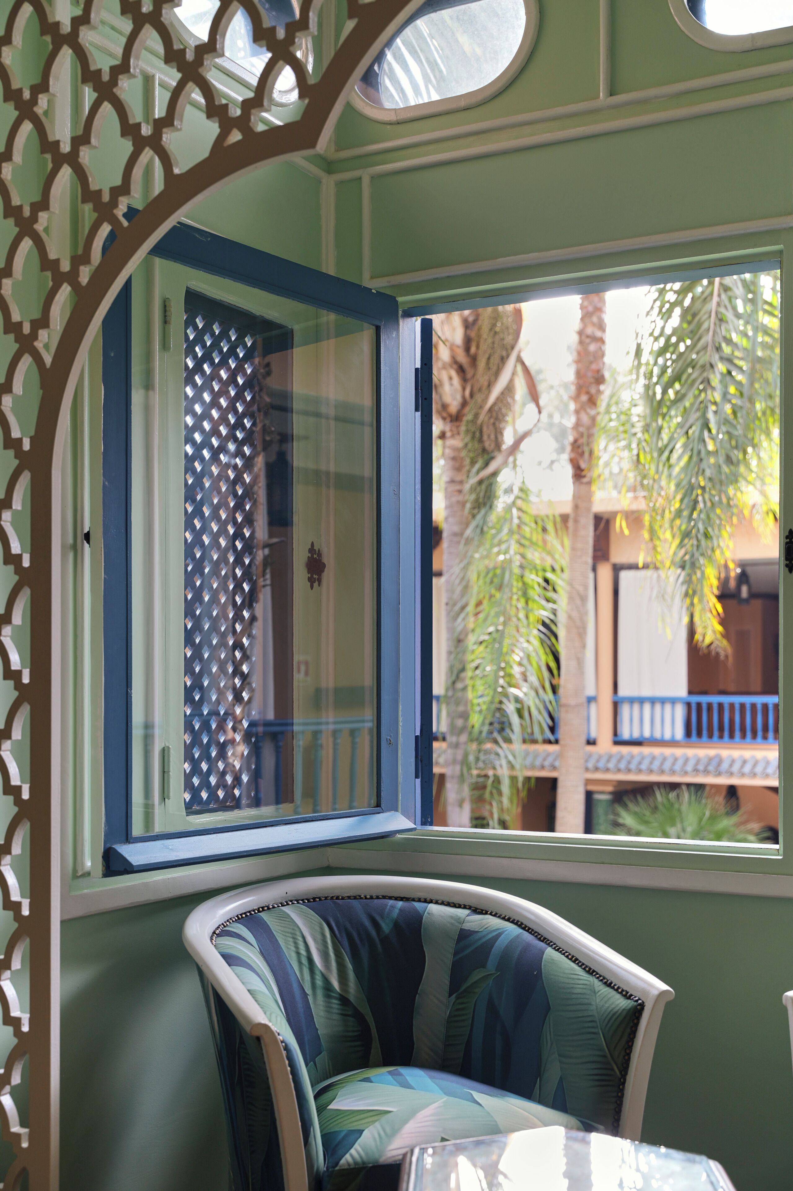 Una habitación con ventana, una silla y vistas a palmeras.