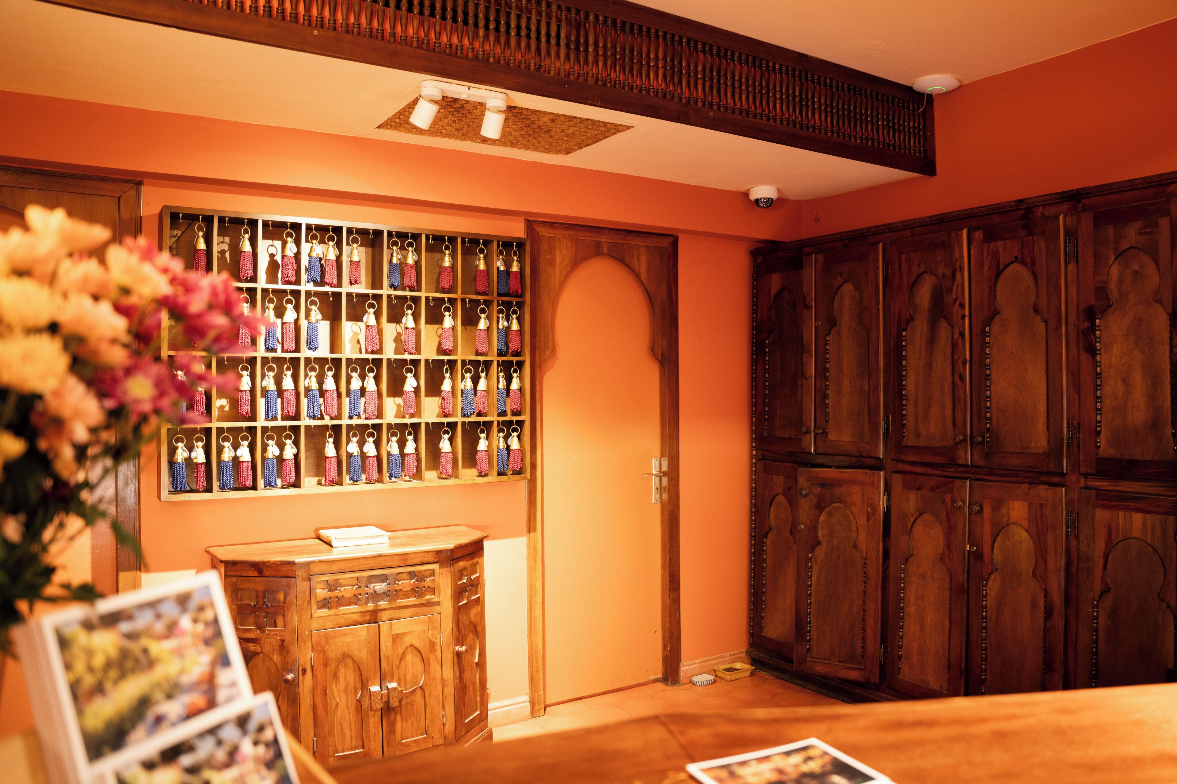 A room with wooden cabinets, a wall-mounted display of keychains, and a wooden desk with a vase of flowers.