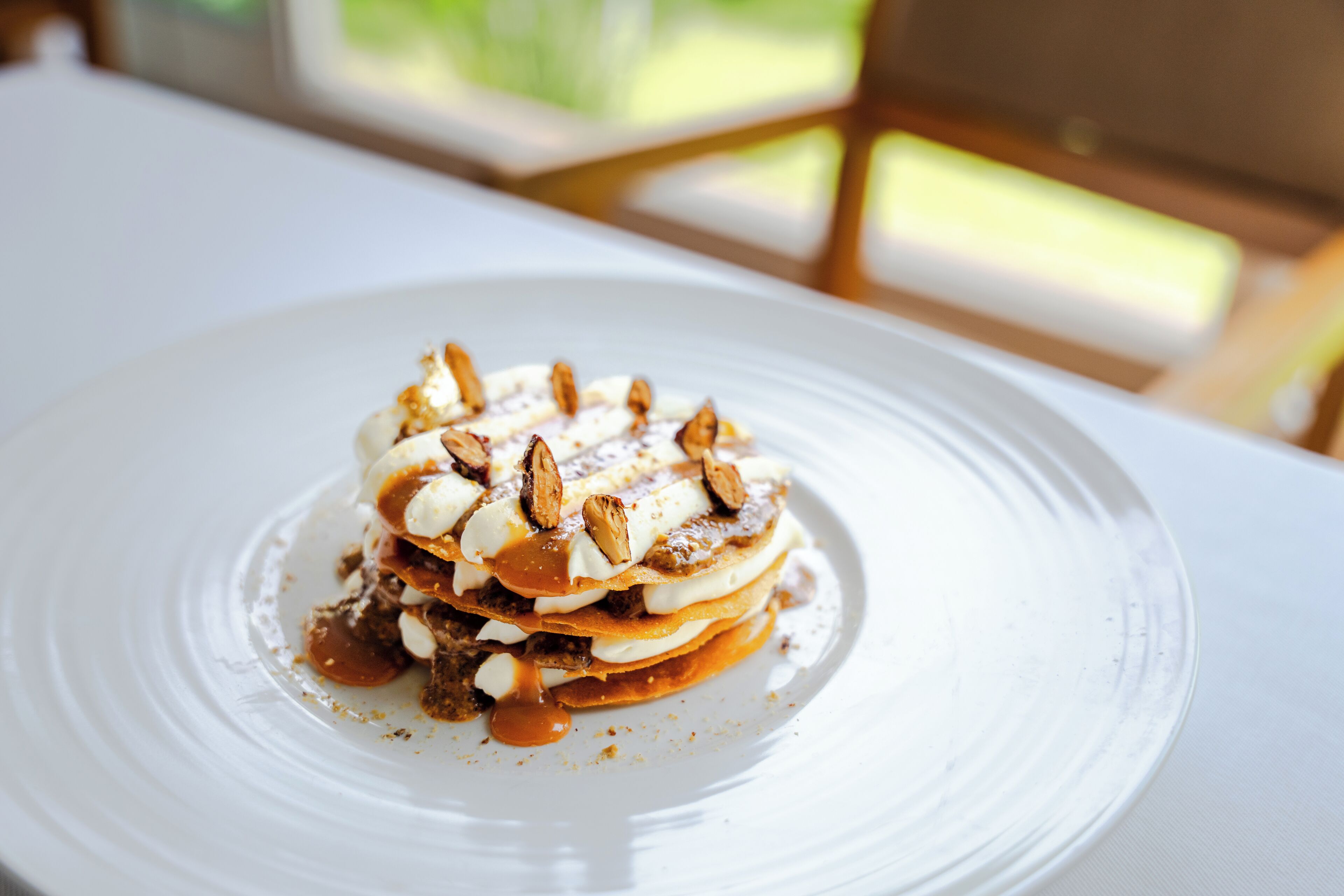 A dessert on a white plate with caramel sauce and nuts.