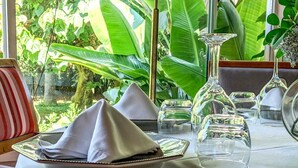 A table set with a plate, napkins, a fork, a glass, and a vase with flowers.