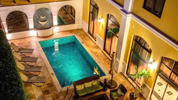 Una piscina interior con suelo de baldosas, rodeada de sillones de descanso y un sofá.