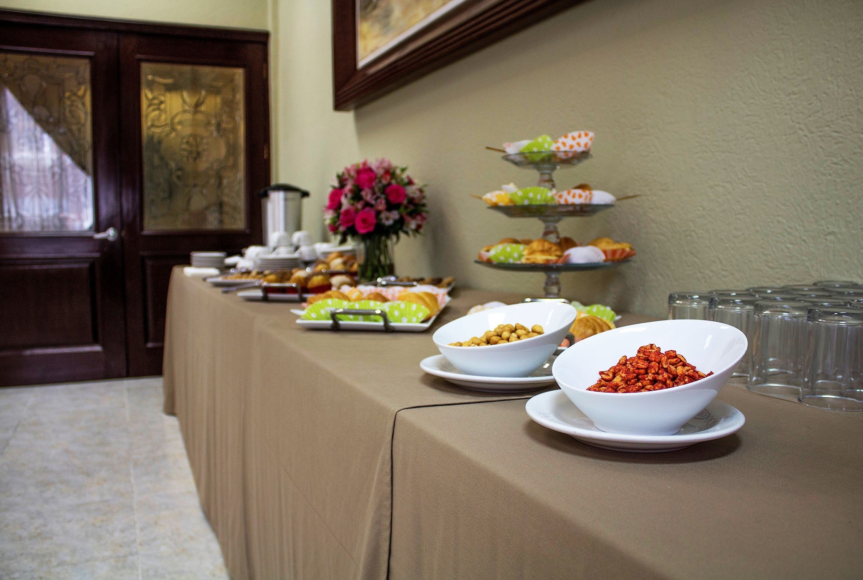 Una mesa de buffet con diversos alimentos y un florero con flores.