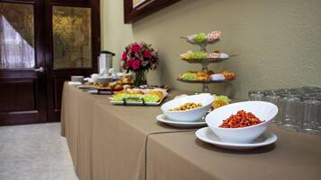 Una mesa de buffet con diversos alimentos y un florero con flores.