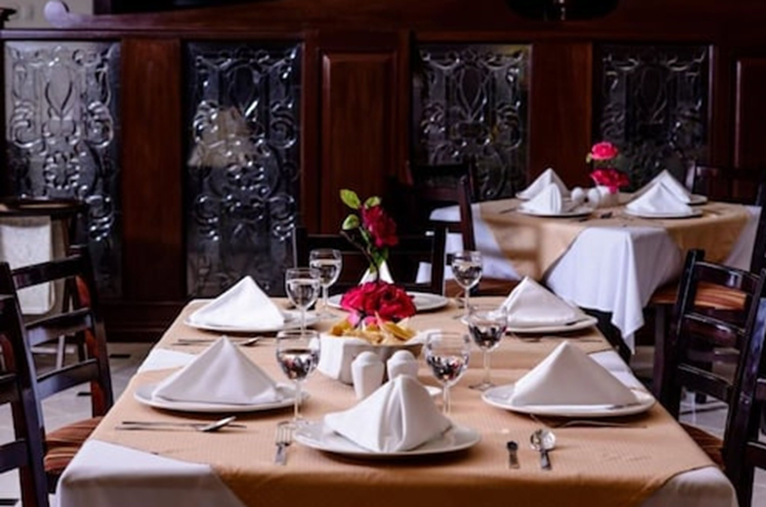A dining area with a long table set for a meal, featuring white napkins, plates, and glasses.