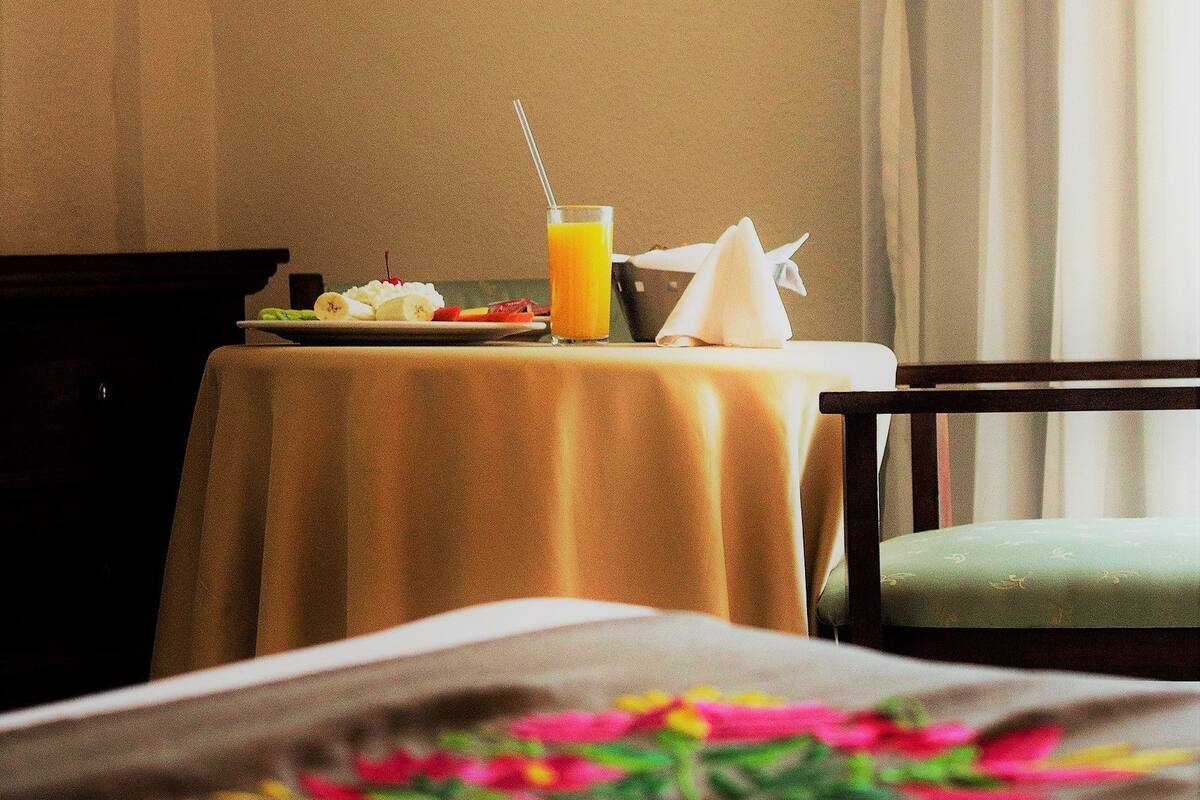 Een hotelkamer met een bed, een ontbijttafel en een raam met gordijnen.