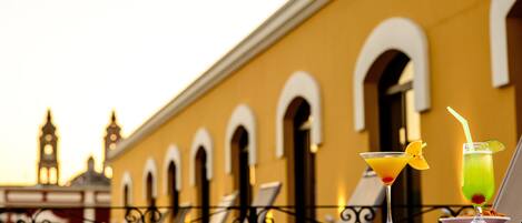 Un edificio amarillo con ventanas de arco y un balcón con dos bebidas.