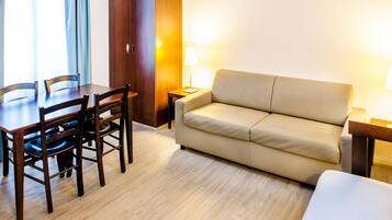 Ein Hotelzimmer mit einem Holztisch, vier Stühlen, einem beigen Sofa und zwei Nachttischlampen.