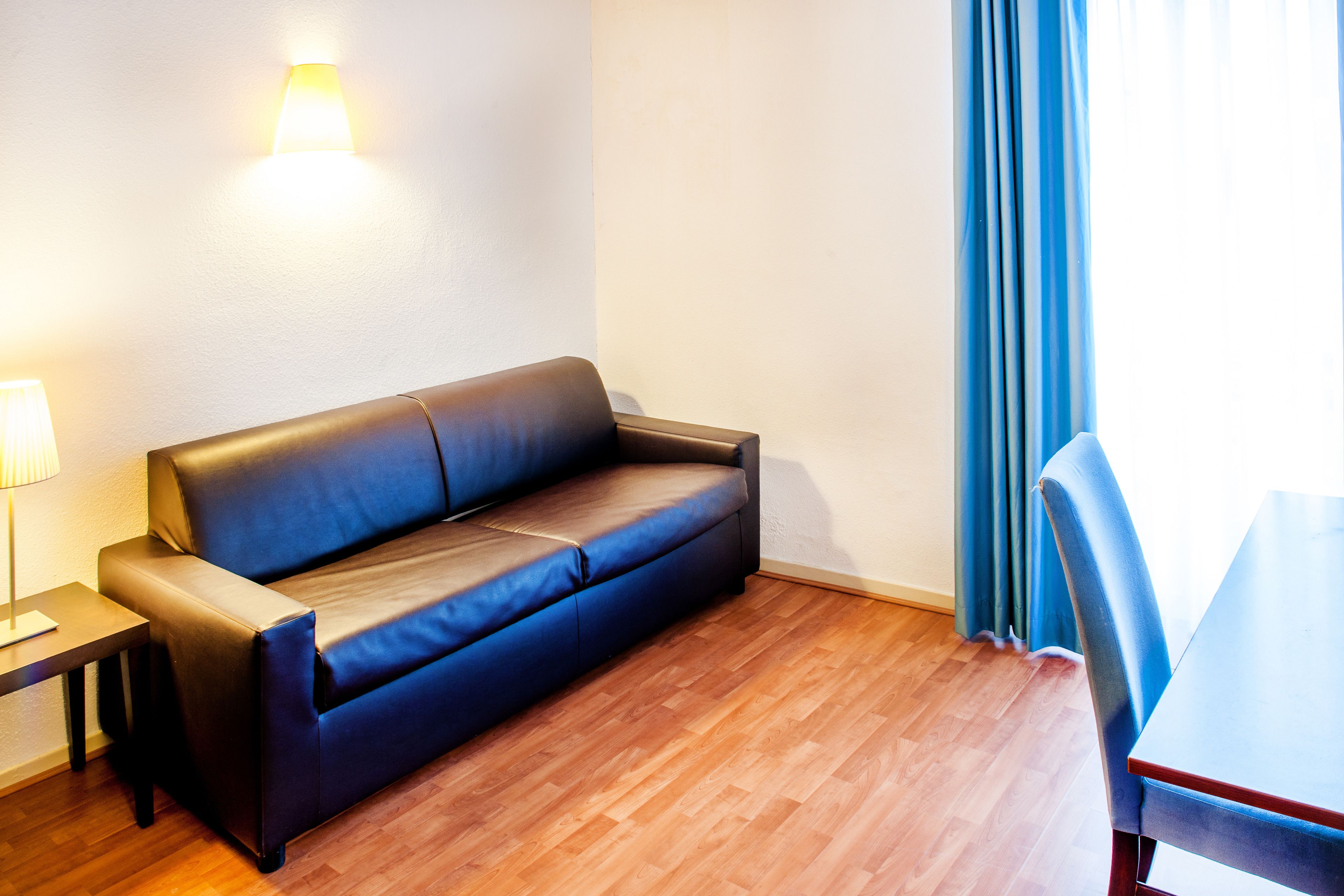 A room with a sofa, a table, and a lamp.