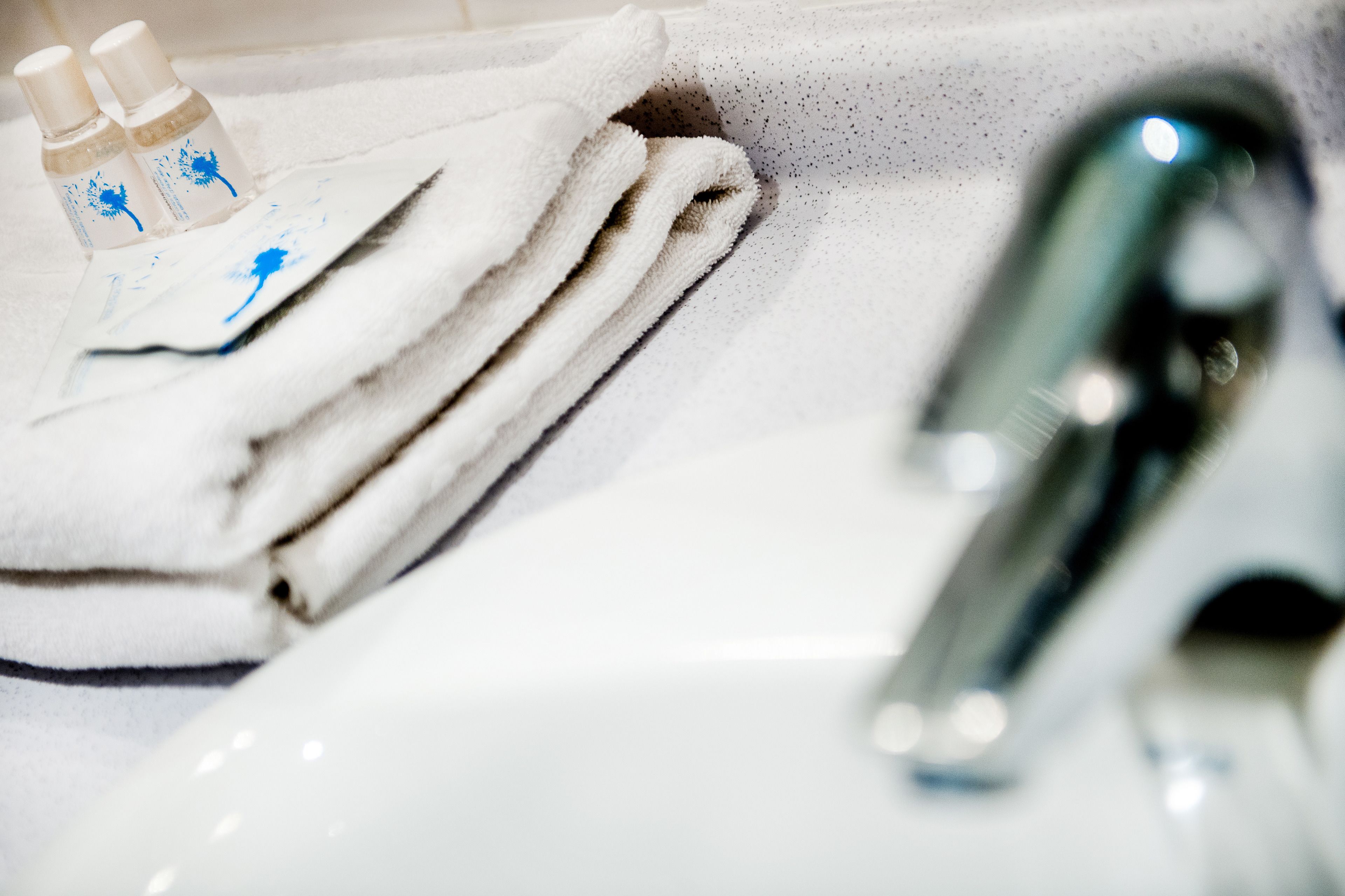 A bathroom sink with a white towel and two bottles of liquid soap.
