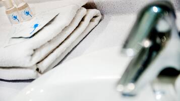 A bathroom sink with a white towel and two bottles of liquid soap.