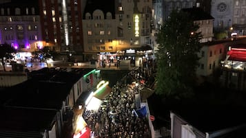 Escena de calle concurrida de noche, con edificios iluminados y una multitud reunida.
