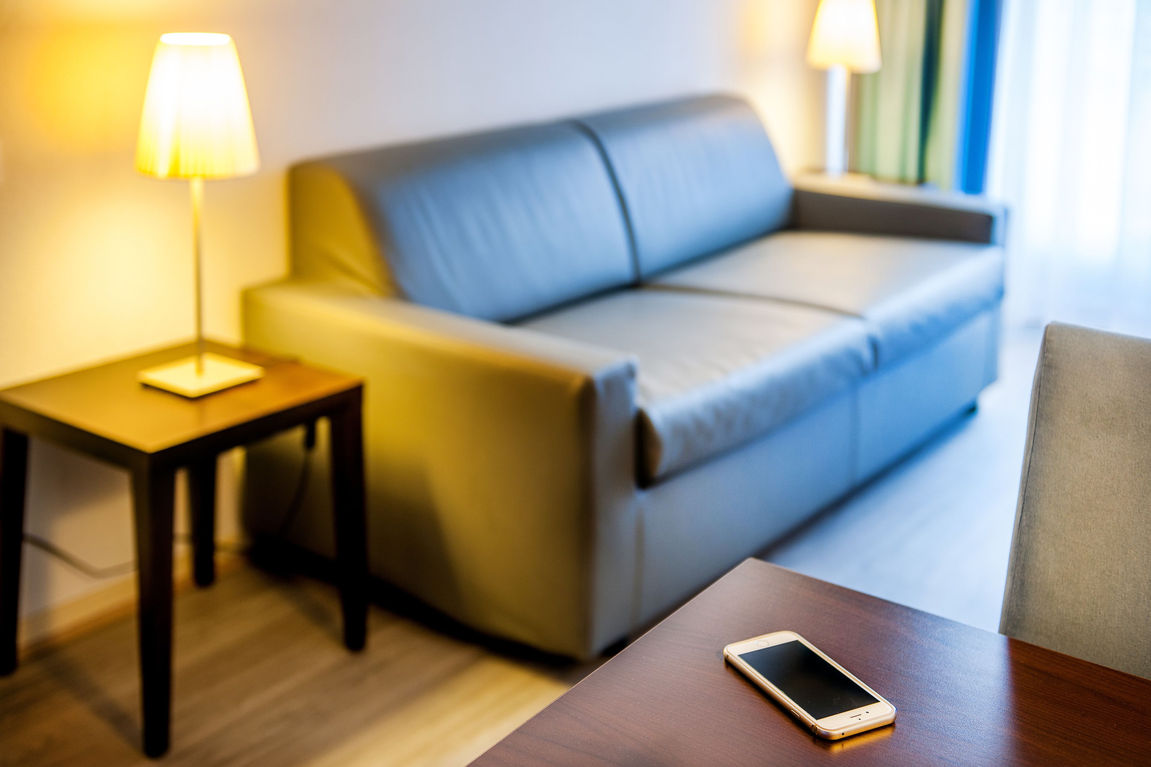 Ein modernes Hotelzimmer mit einer Couch, einem kleinen Tisch und einer Lampe.