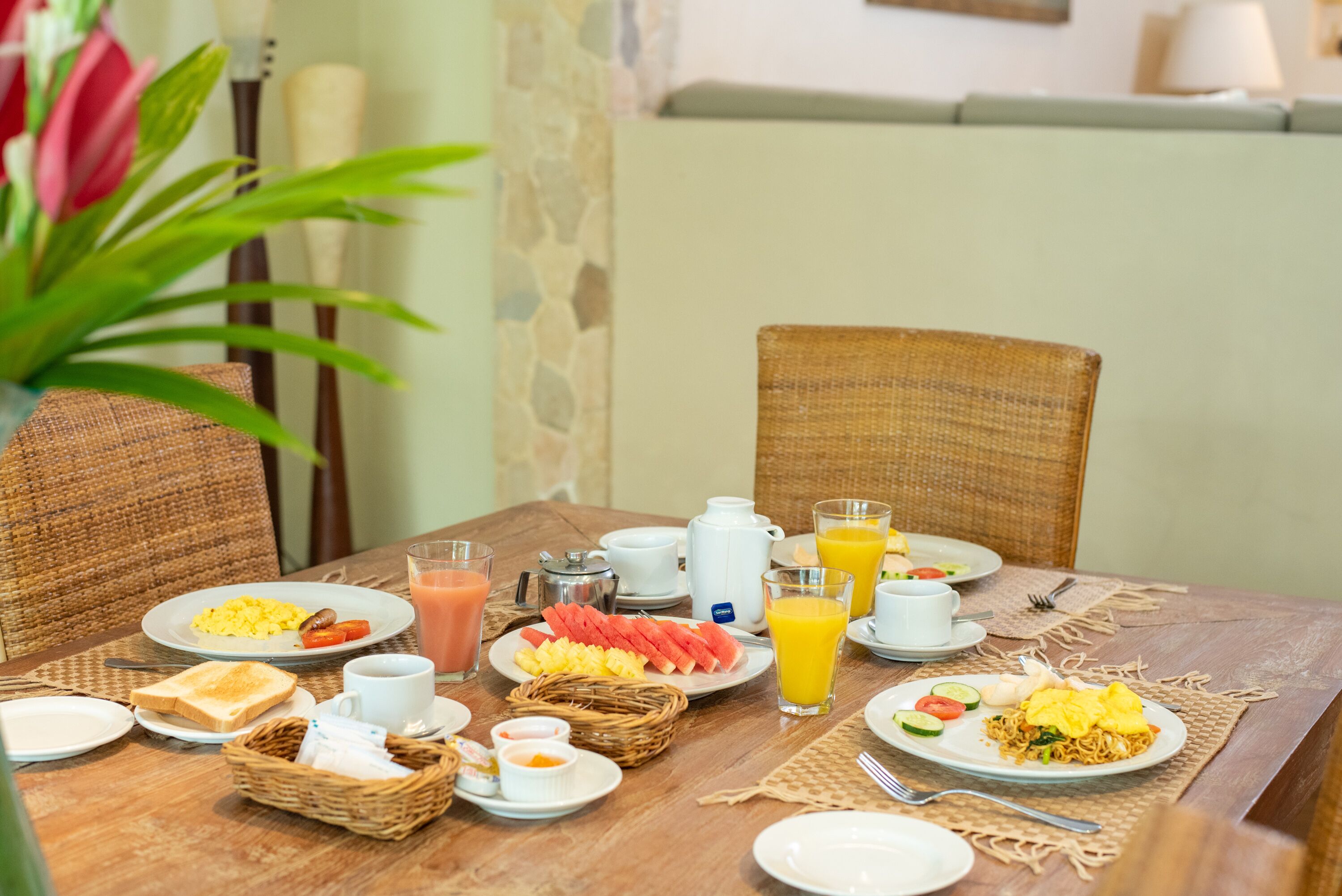 A breakfast table set with plates of food, including eggs, toast, and fruit, along with cups and glasses of juice.