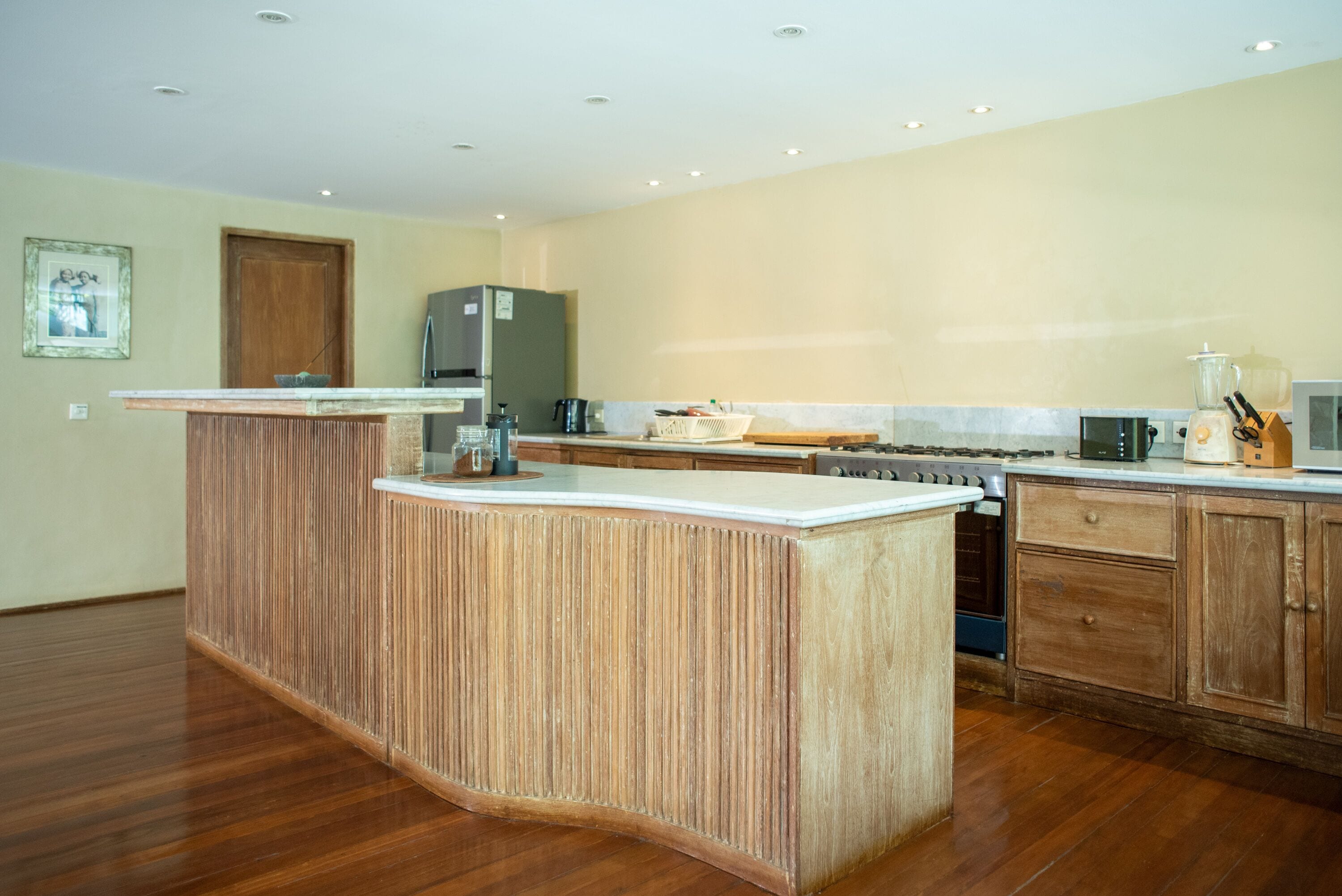 Una cocina con isla central, armarios de madera y un refrigerador.