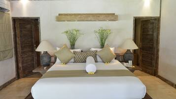 A large bed with a wooden headboard, two bedside tables with lamps, a small vase with flowers, and a wooden shelf above the bed.