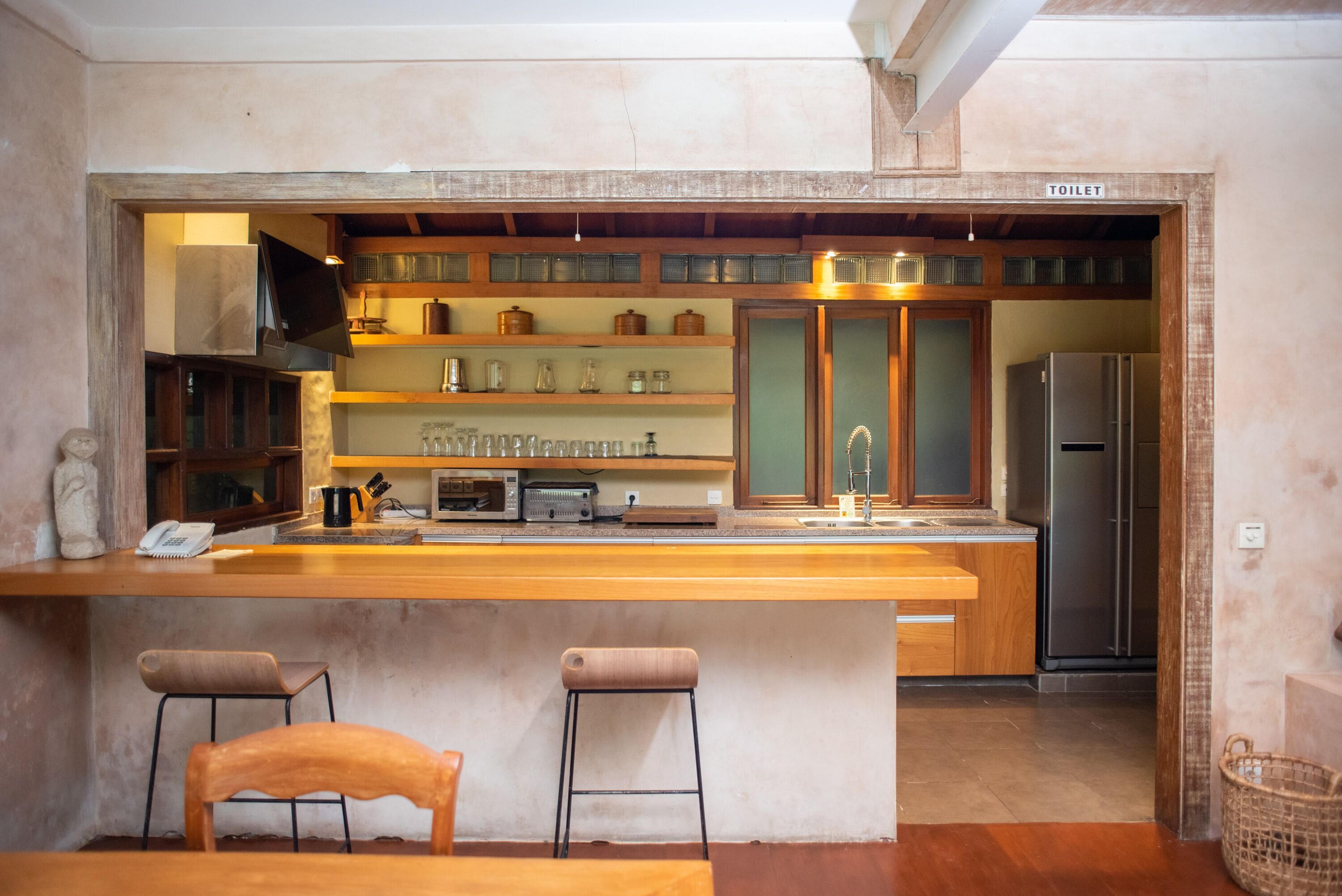 A kitchen with wooden bar stools, a refrigerator, and a sink.