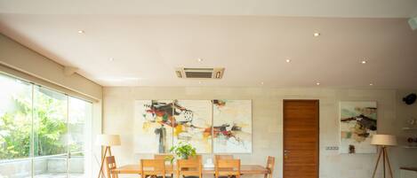 A modern dining area with a glass partition, wooden furniture, and abstract wall art.