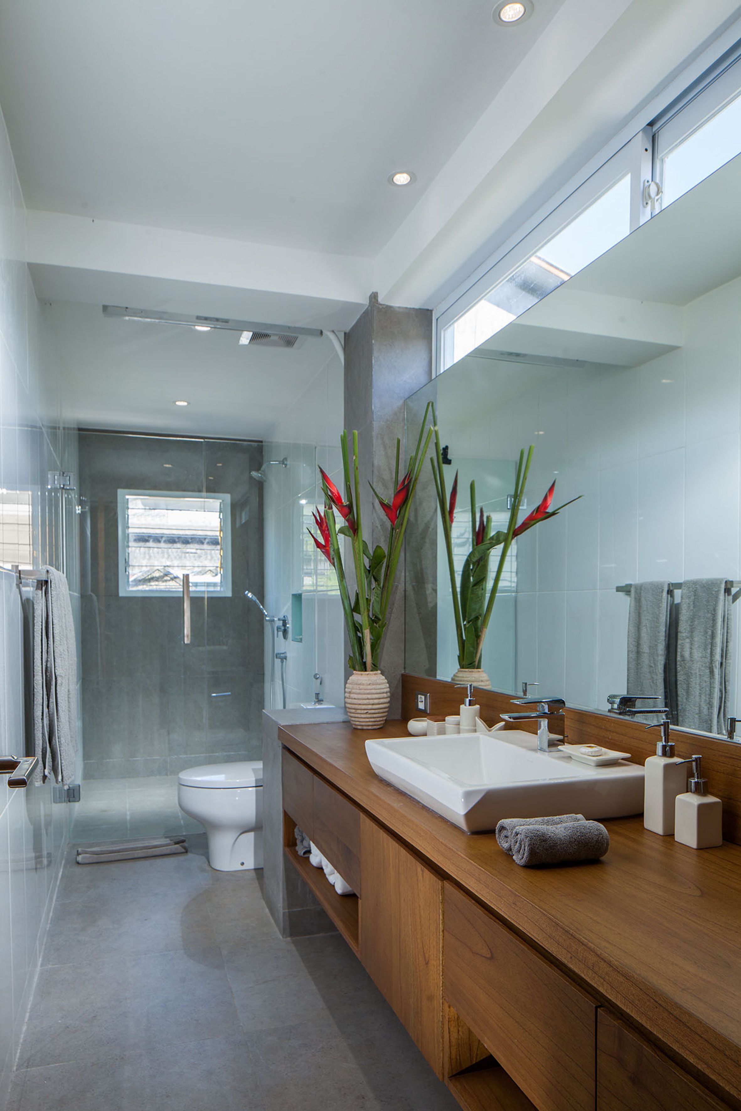 A modern bathroom with a glass shower enclosure, a white sink, and a large mirror.