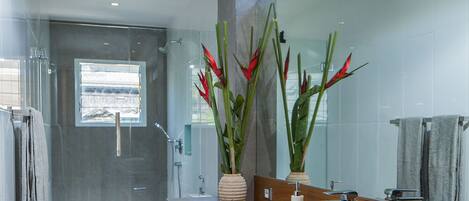 A modern bathroom with a glass shower enclosure, a white sink, and a large mirror.