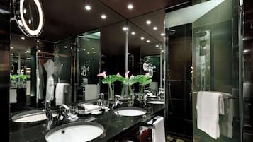 A modern bathroom with two sinks, a large mirror, and a glass shower enclosure.