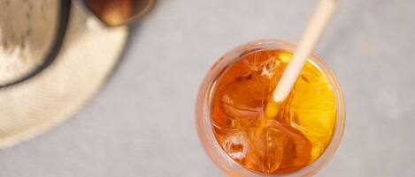 A drink with a straw and a slice of lemon, a pair of sunglasses, and a straw hat.