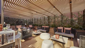 Una terrazza esterna con pavimento in legno, sedute imbottite e un pergolato.
