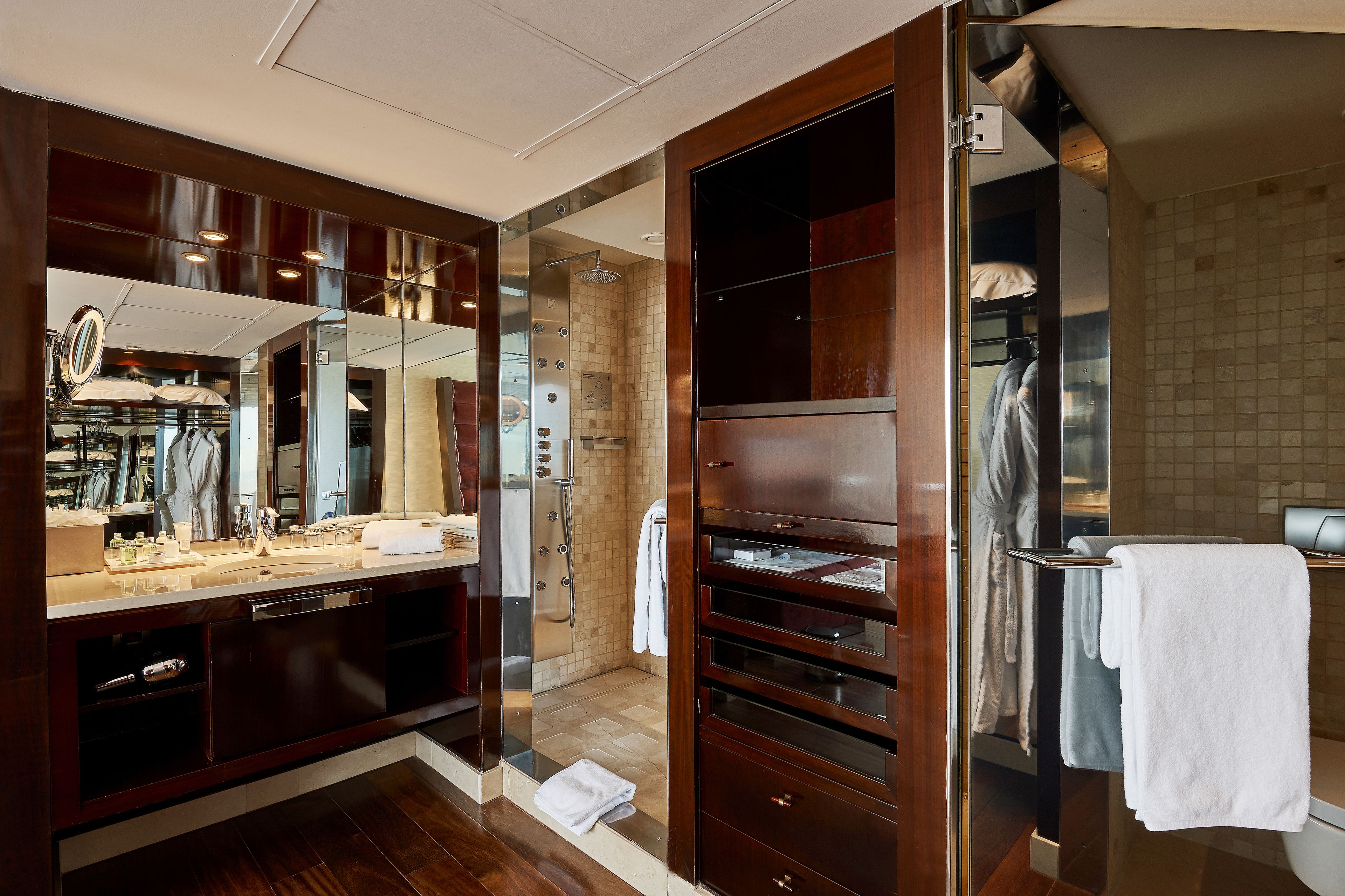 Un baño moderno con un espejo grande, cabina de ducha y tocador con lavabo y toallero.
