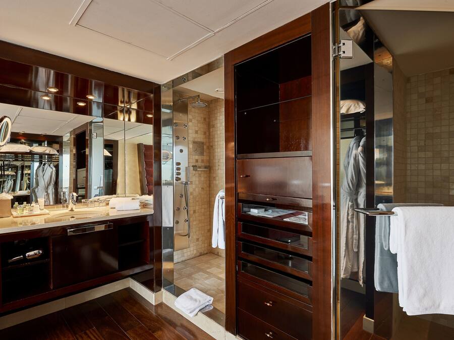 A modern bathroom with a large mirror, a walk-in shower, and a vanity with a sink and towel rack.