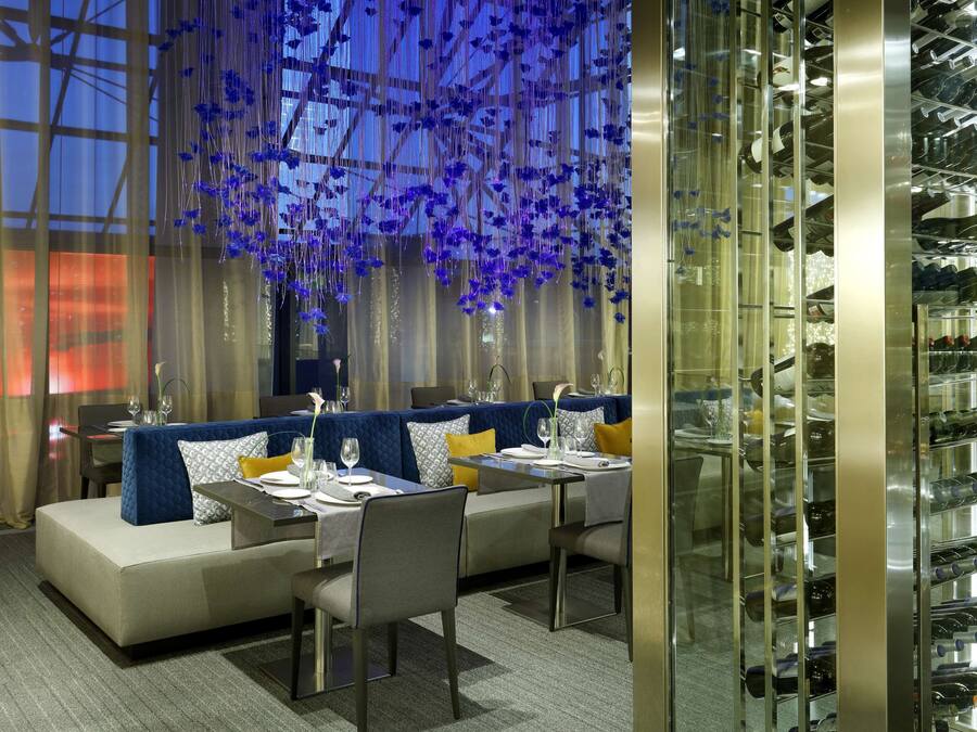 A modern dining area with a sofa set, tables, and a wine rack.