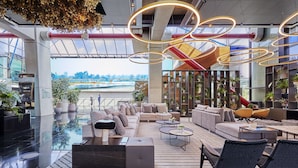 Un hall d’entrée spacieux au design moderne, comprenant un grand espace salon, une machine à café et une vue sur une rivière.