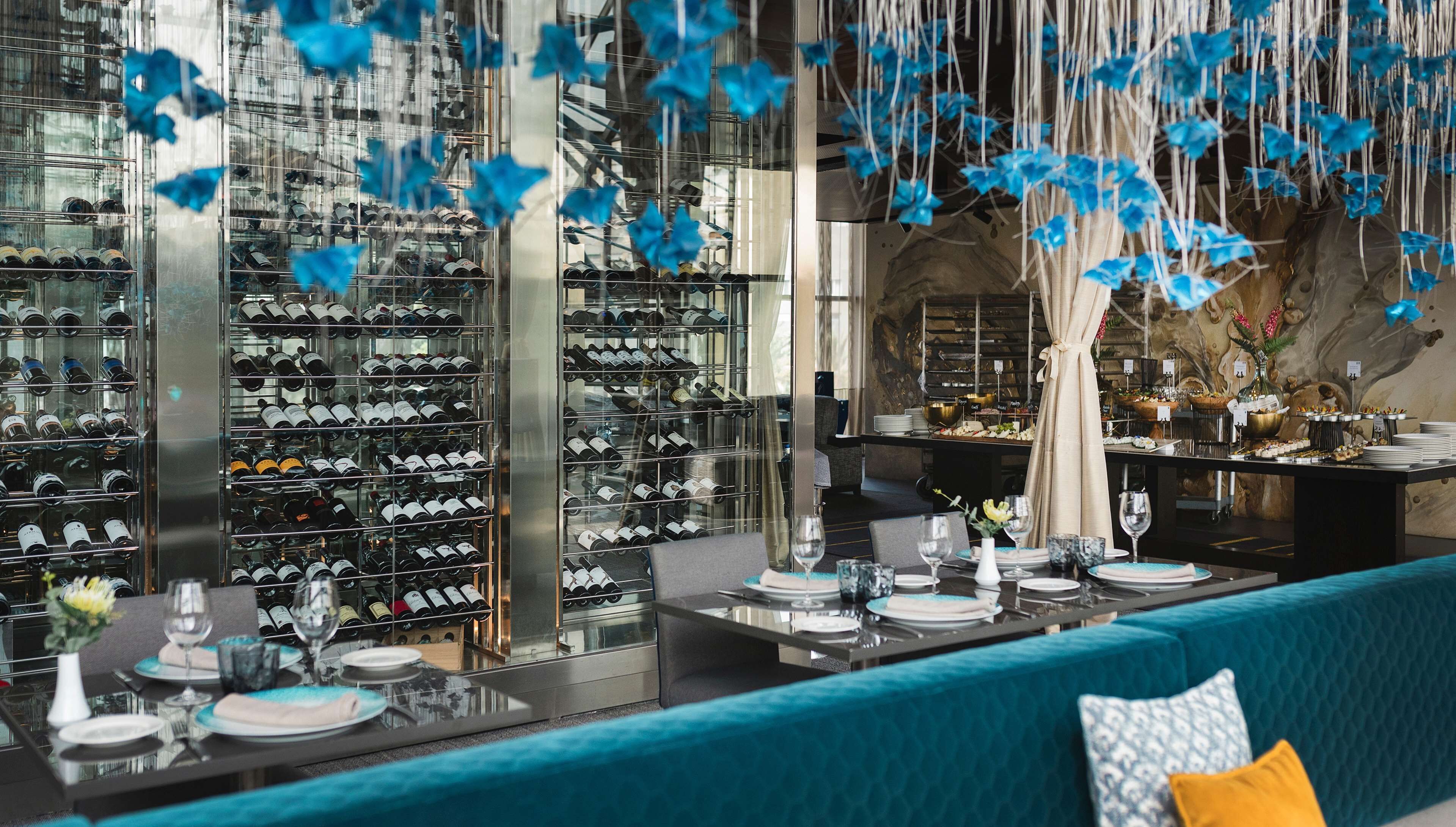 Un restaurant doté d’une cave à vin, de sièges de couleur turquoise et de décorations bleues suspendues.