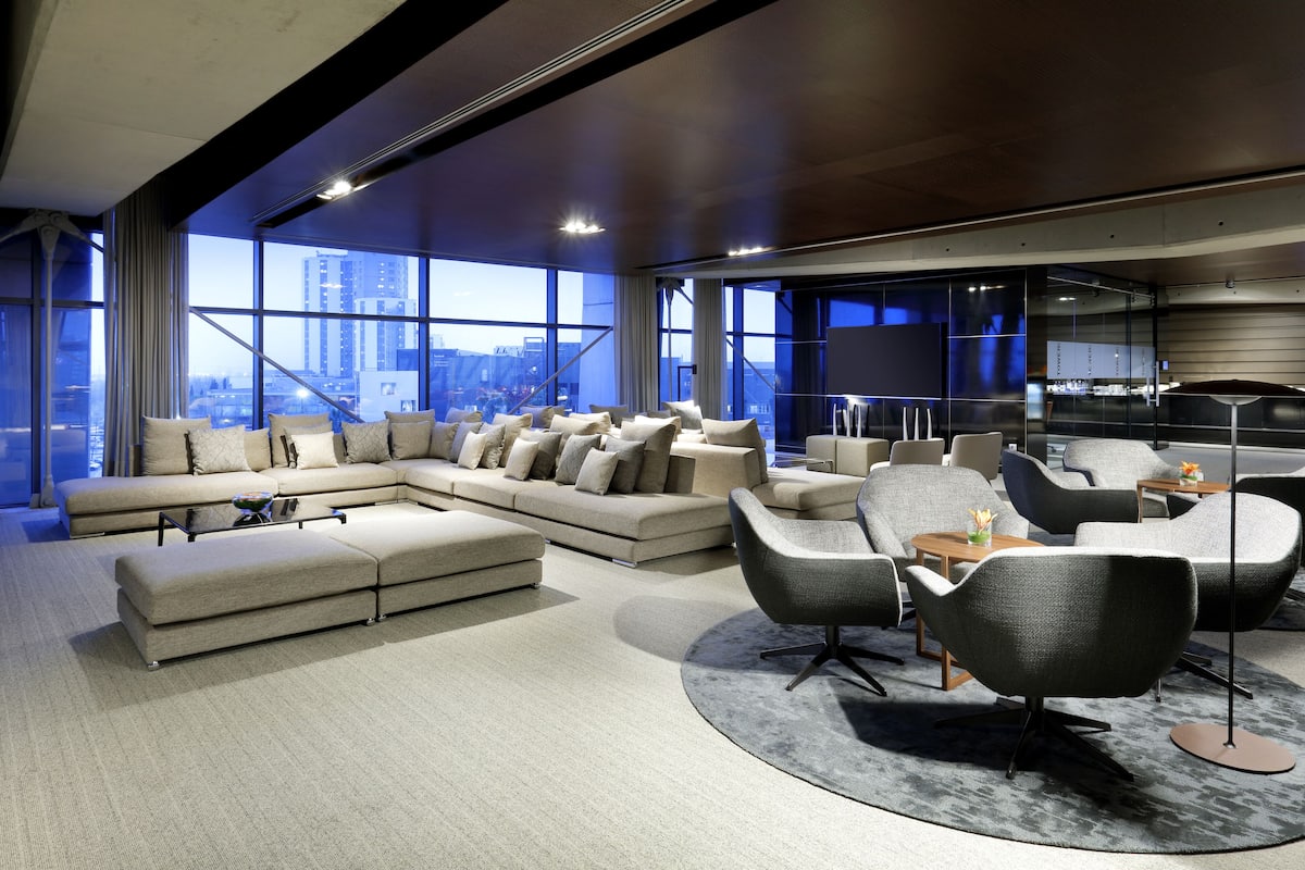 A modern living room with a sectional sofa, grey armchairs, and a coffee table.