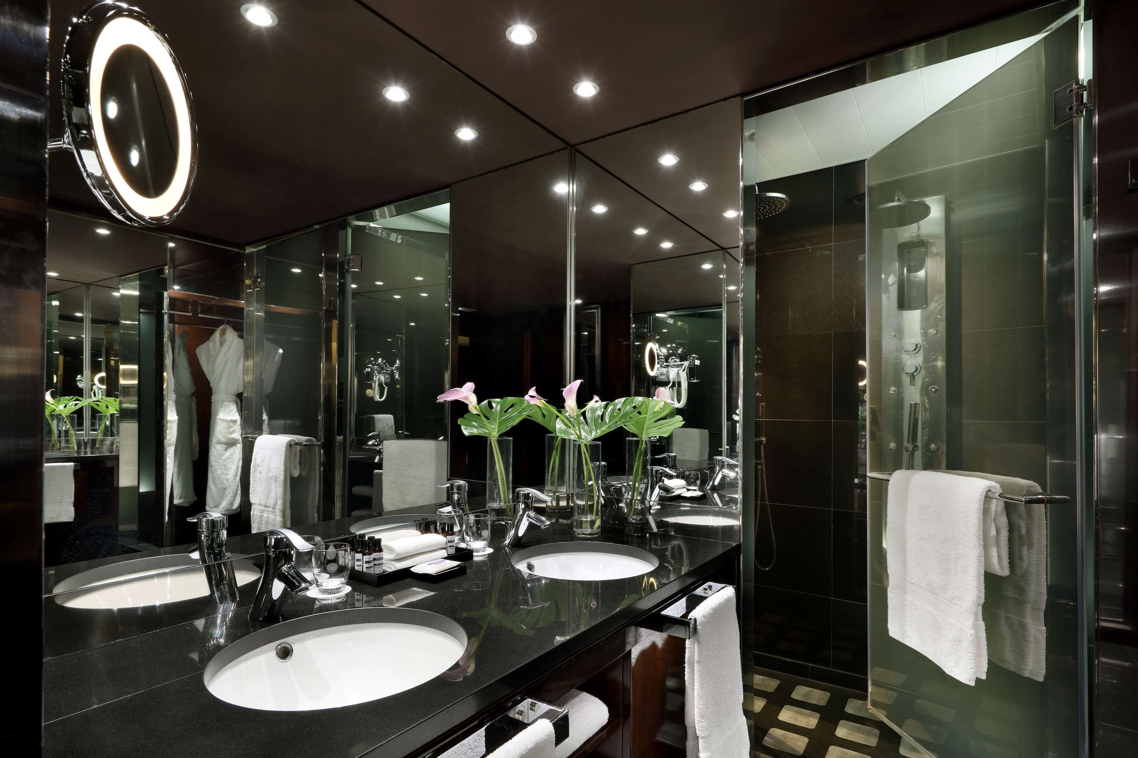 A modern bathroom with two sinks, a large mirror, and a glass shower enclosure.
