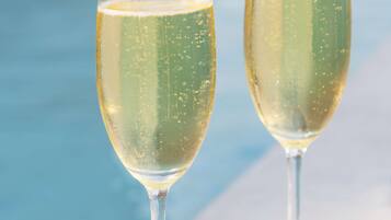 Two champagne glasses by a poolside.