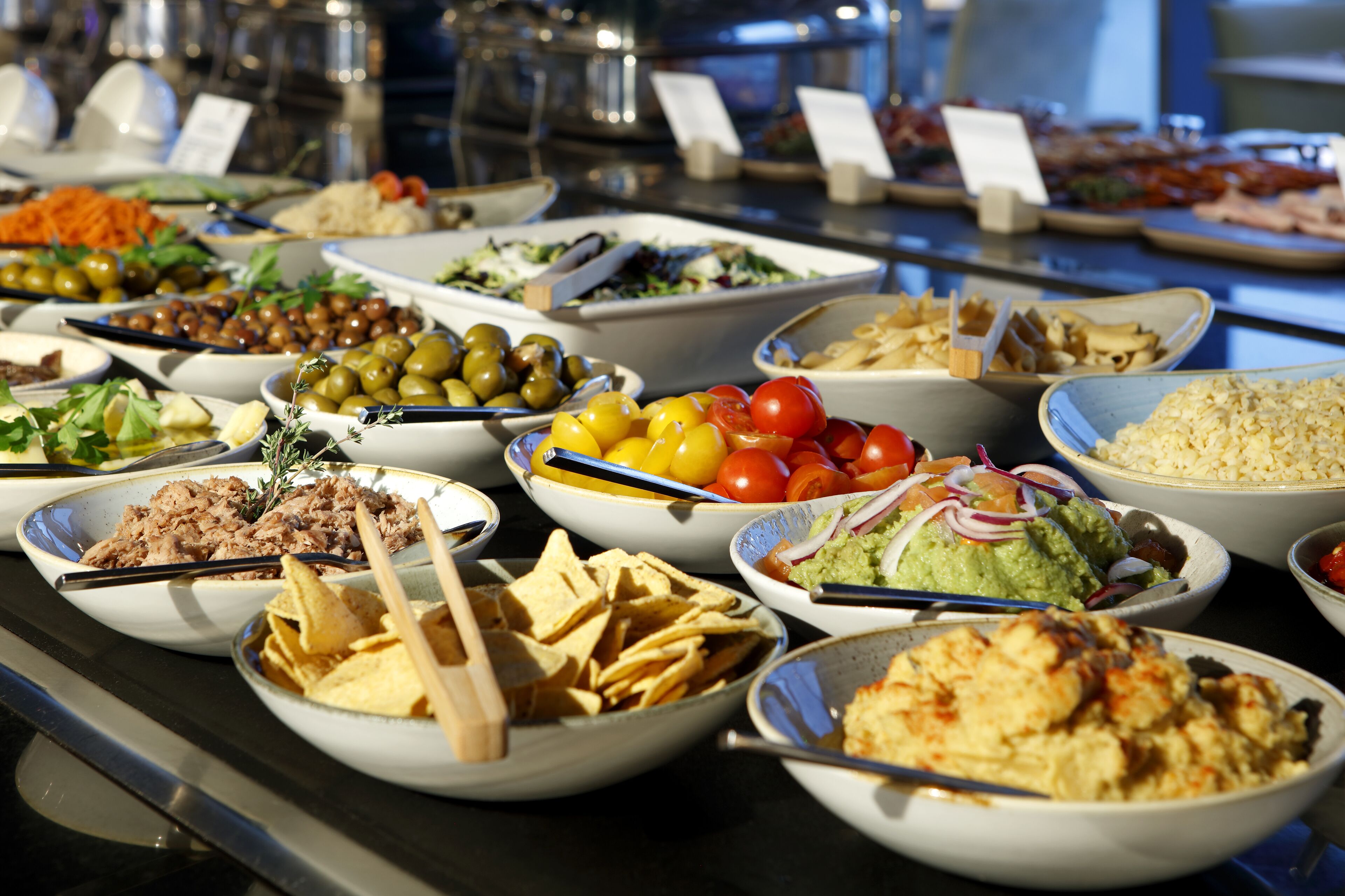 Un buffet proposant une variété de plats, notamment des salades, des fruits et des sauces.