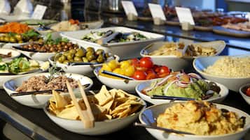Un buffet proposant une variété de plats, notamment des salades, des fruits et des sauces.