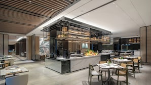 Un restaurant moderne doté d’un bar central, de plusieurs tables et d’un décor intérieur contemporain.