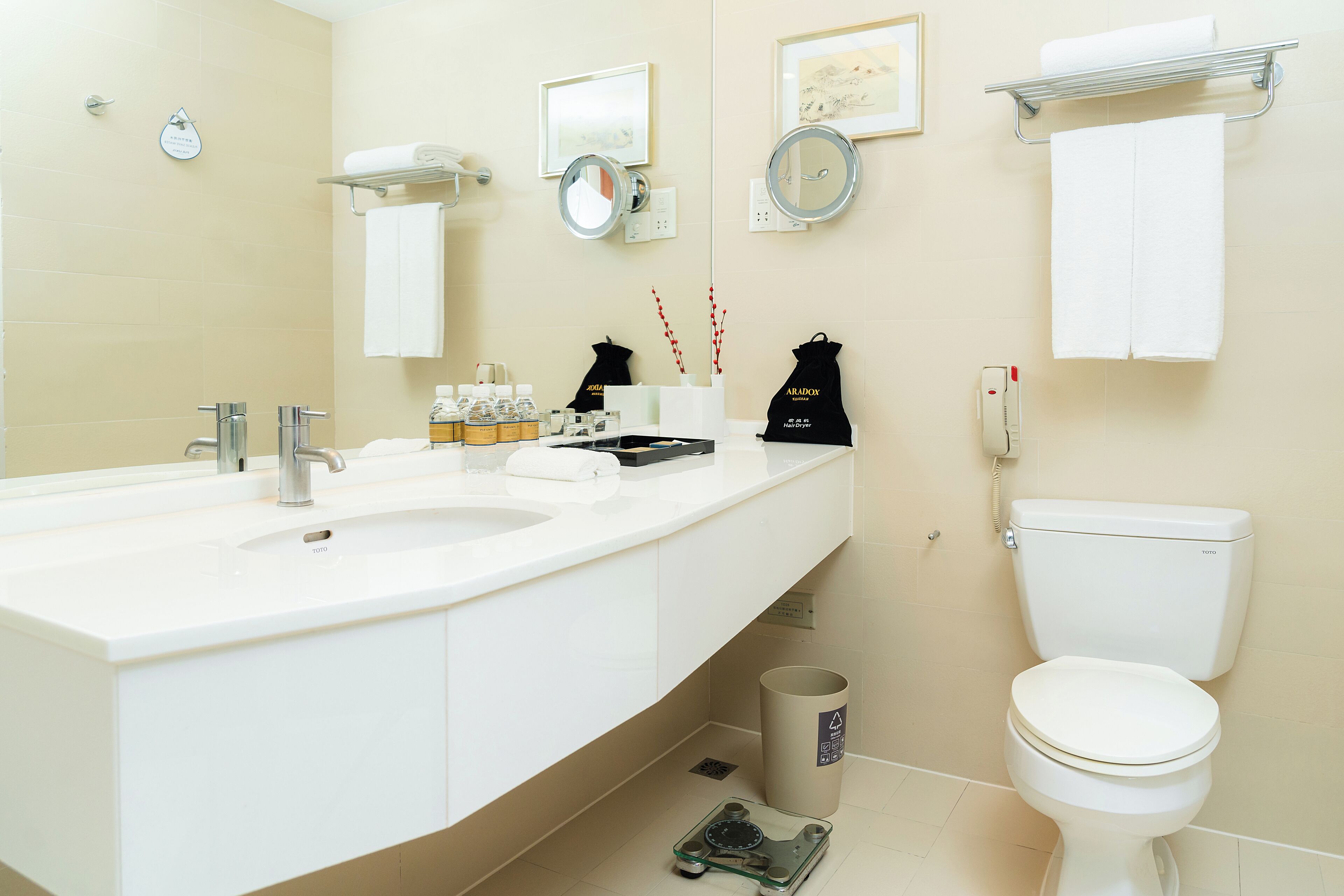 Ein modernes Badezimmer mit einem großen Waschbecken, zwei Spiegeln, einer Toilette und einem Mülleimer.