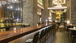 A bar area with a long counter, multiple stools, and a variety of bottles on shelves. - Paradox Kunshan (Suzhou)