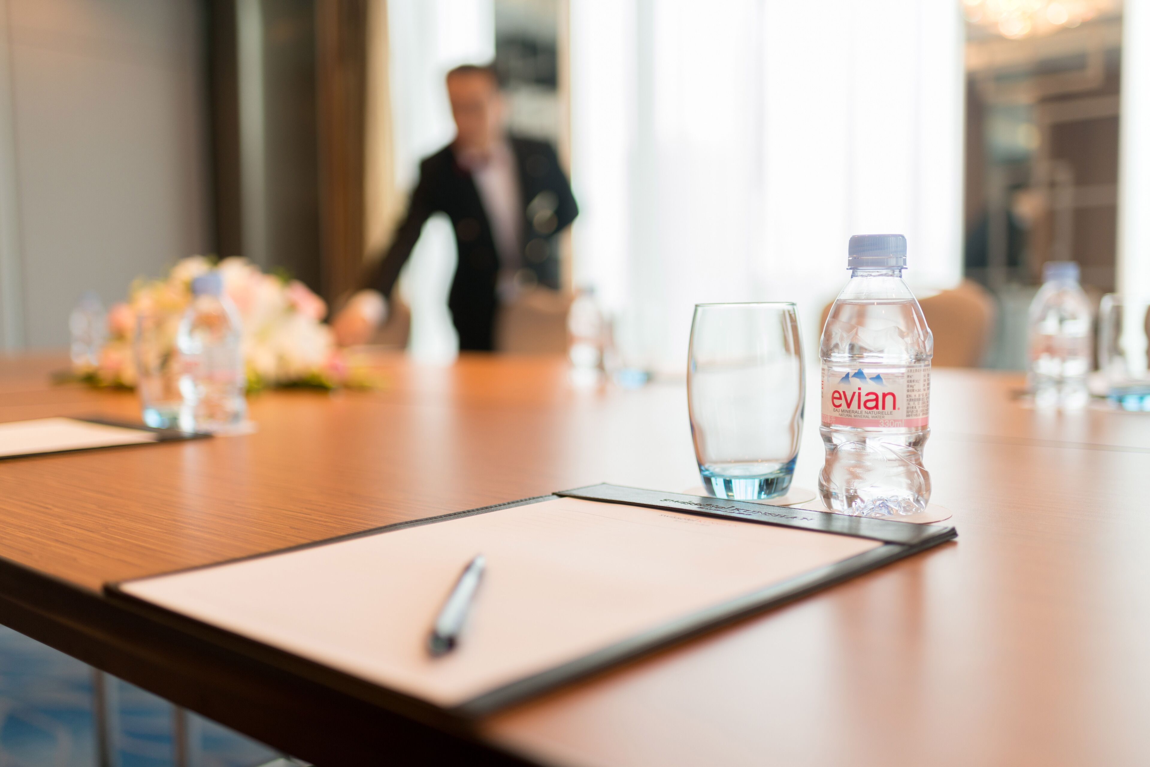 A conference table with water bottles, glasses, and a pen.