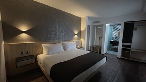 A modern bedroom with a large bed, bedside tables, a wardrobe, and a walk-in closet. - Fato Hotel (Querétaro)