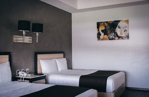 Habitación de hotel con dos camas, una mesita de noche con teléfono y un cuadro en la pared.