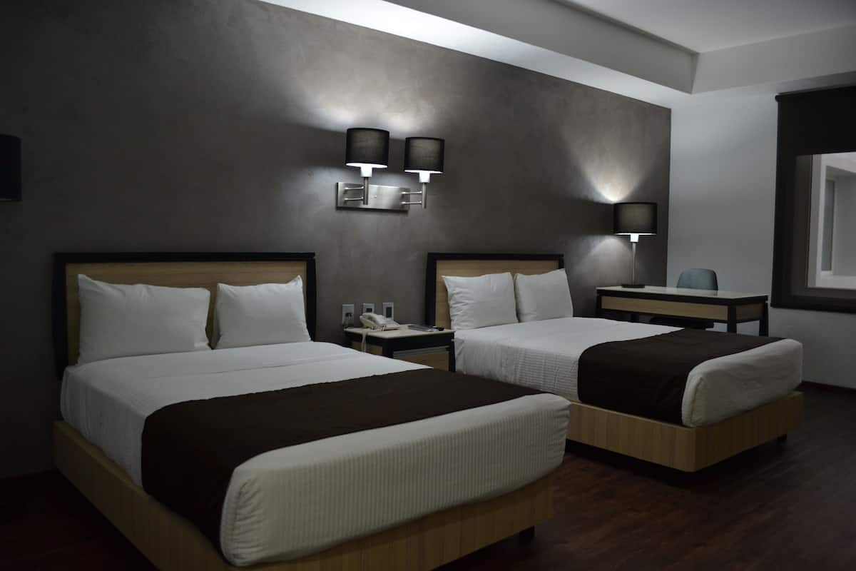 Hotellihuone, jossa on kaksi sänkyä, työpöytä ja tuoli.