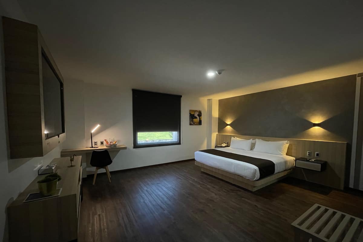Moderni hotellihuone, jossa on suuri sänky, työpöytä ja ikkuna, josta on näkymä.